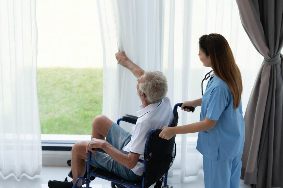Free Image of Healthcare worker wheeling elderly patient to the window 