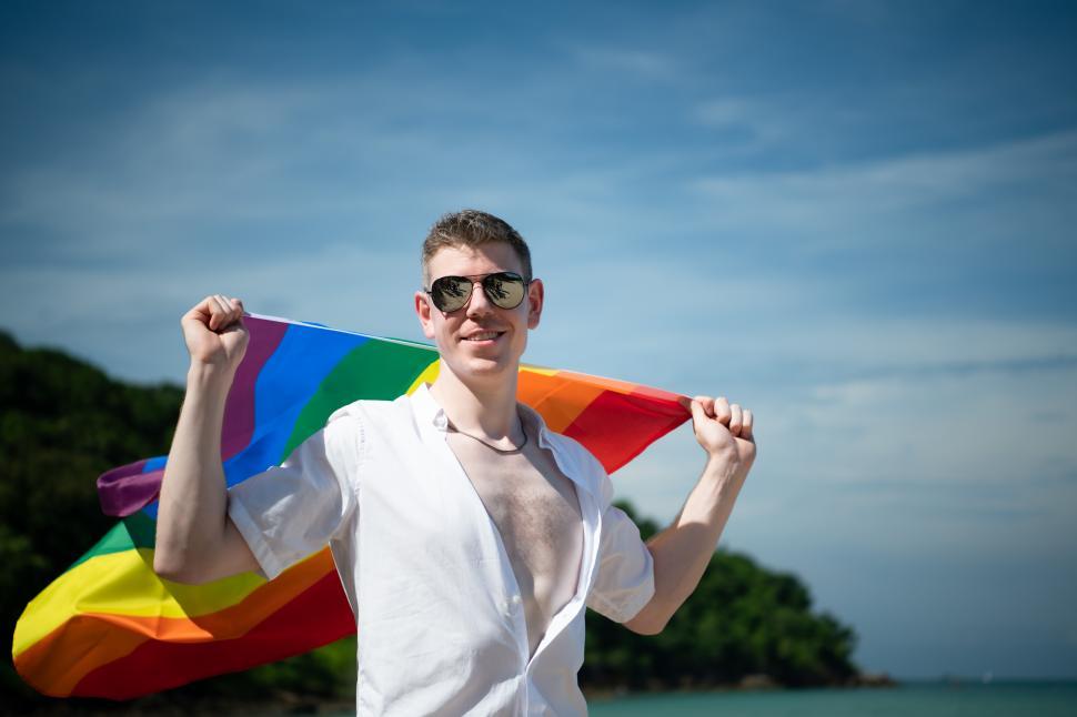 Free Image of Smiling man holding rainbow flag over his shoulders 