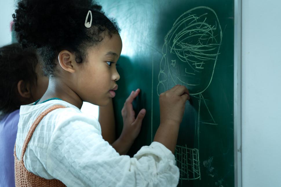 Free Image of A little girl with a brilliant imagination drawing on chalkboard 
