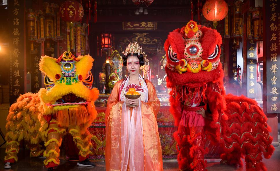 Free Image of Yellow and red lions with woman during Chinese New Year celebration 