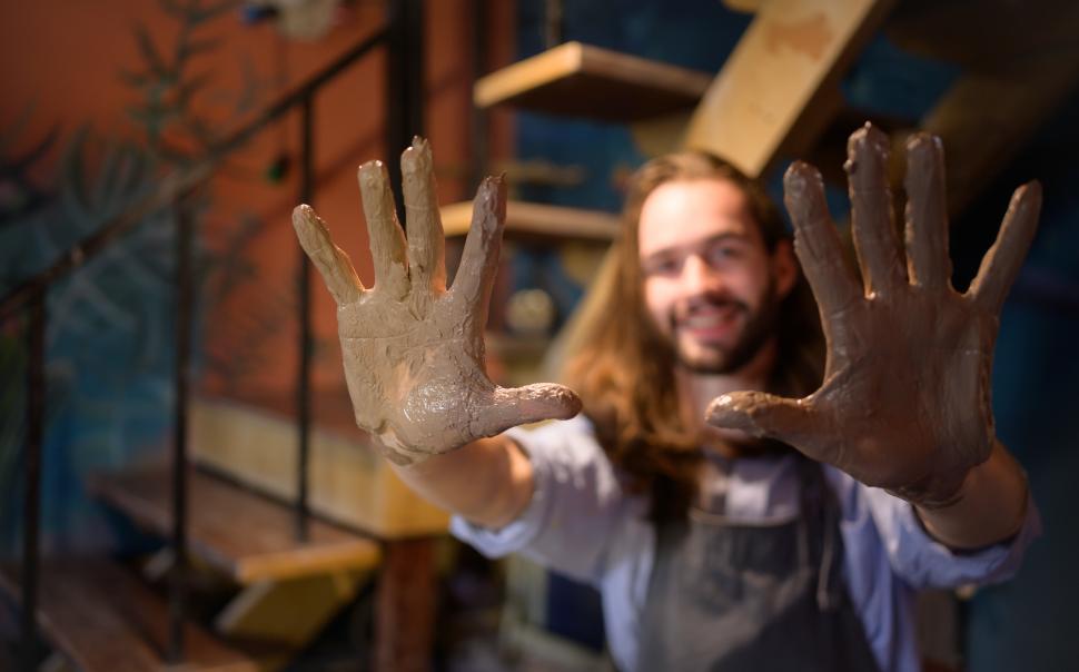 Free Image of Ceramic artist showing off clay-covered hands 