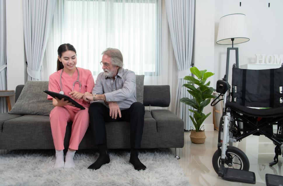 Free Image of Caregiver for an elderly man showing images on a tablet device in home  