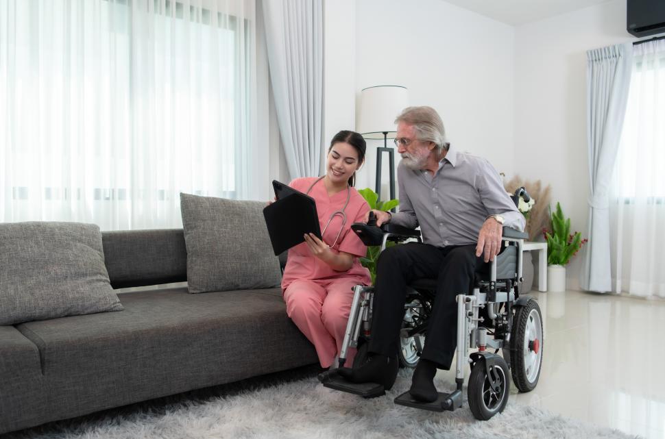 Free Image of Elderly man using wheelchair, visiting with home health care worker 