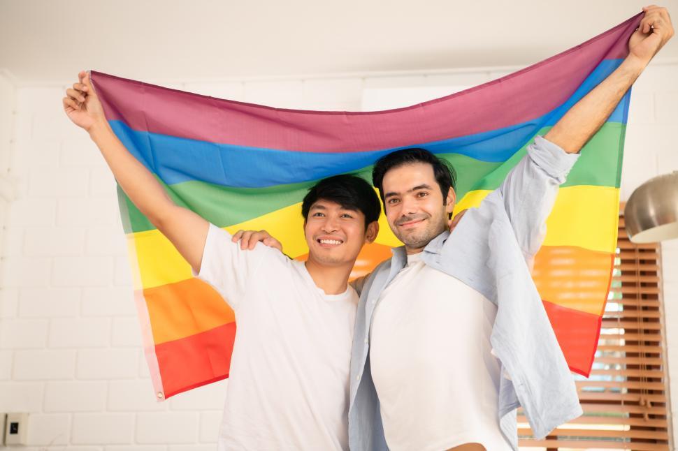 Free Image of Two men holding rainbow pride flag in arms over their heads 
