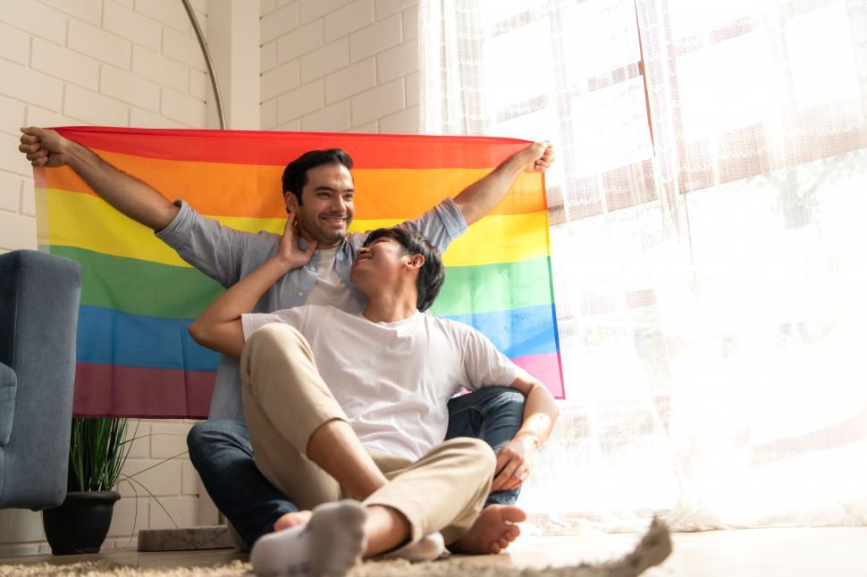 Free Image of Two men celebrate pride together with unfurled rainbow flag 