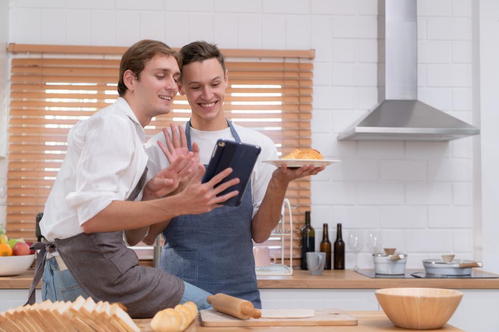 Free Image of Young couple go to the kitchen and learn how to bake cookies online 