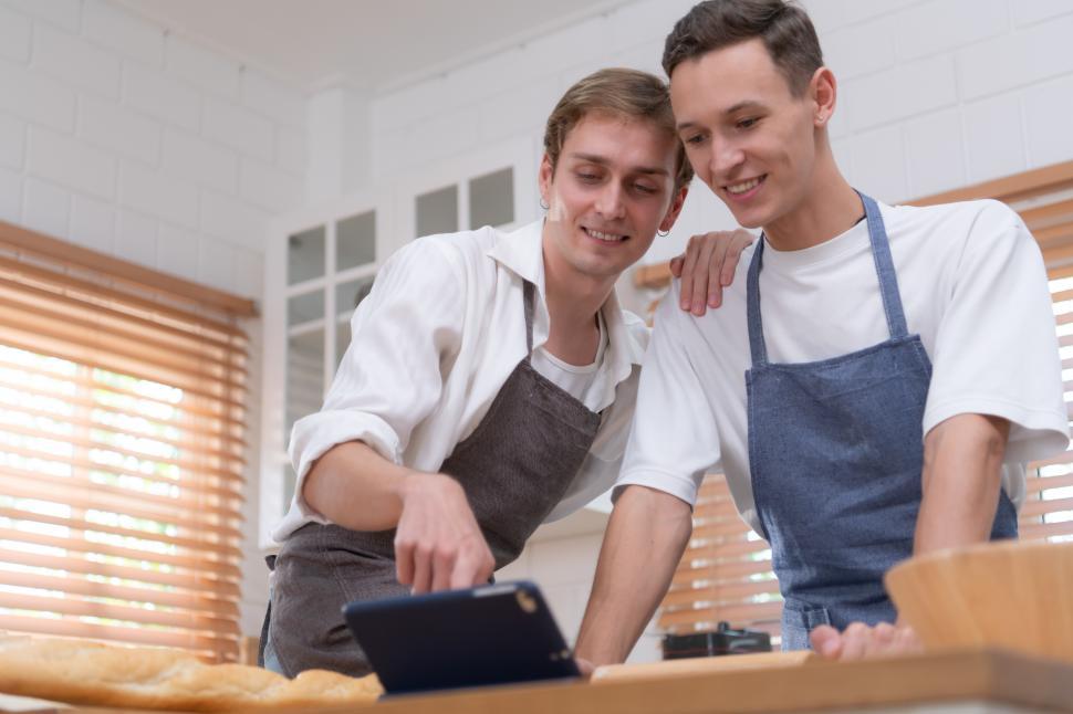 Free Image of Two young men looking at online recipe as they prepare to cook together 