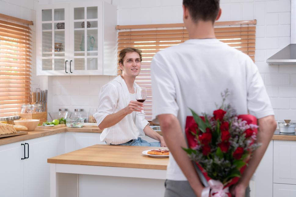 Free Image of Surprise roses as romantic gesture - young LGBT couple in the kitchen 