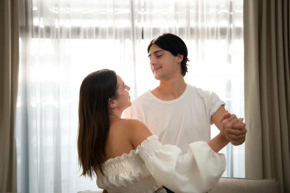 Free Image of Young couple in the living room of the house in the morning, dancing together 