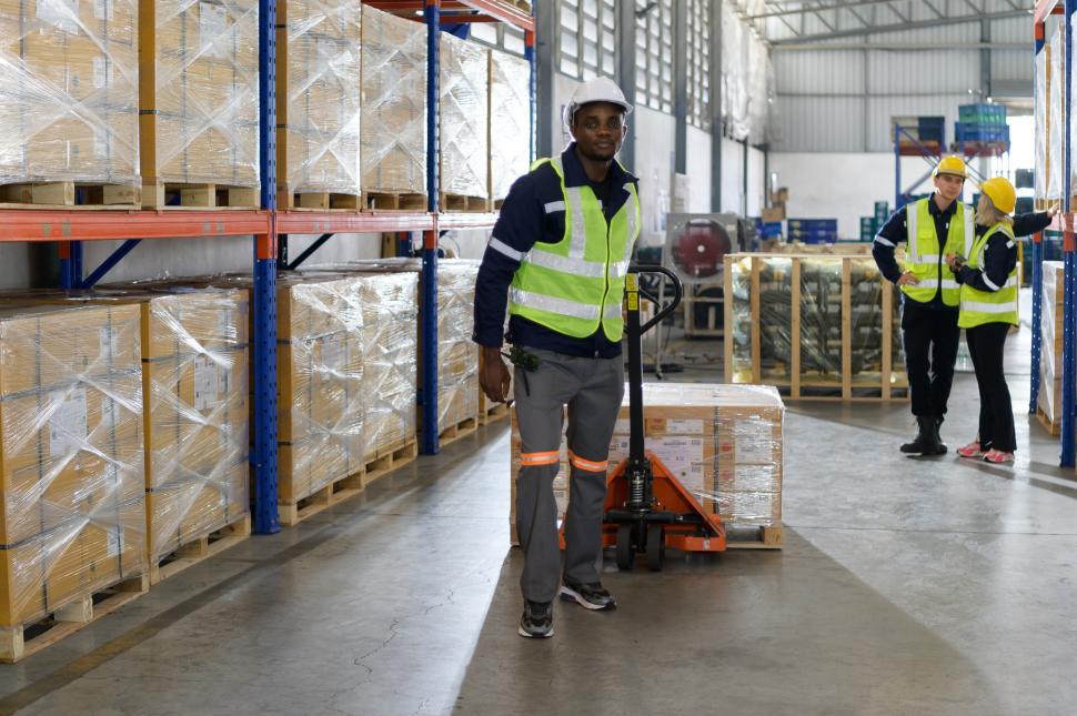 Free Image of Worker in auto parts warehouse use a handcart for heavy items 