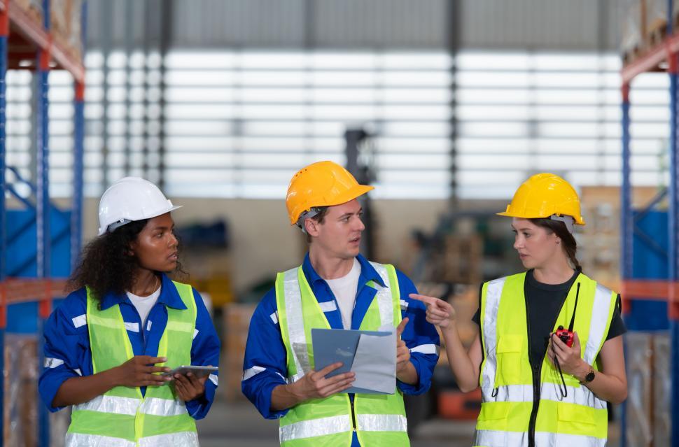 Free Image of Group of employees in an auto parts warehouse, wearing safety gear 