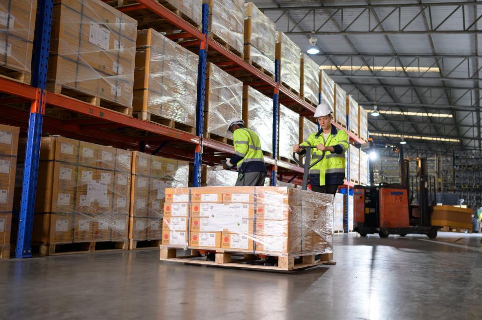 Free Image of Worker in auto parts warehouse use a handcart or pallet jack to move a pallet 