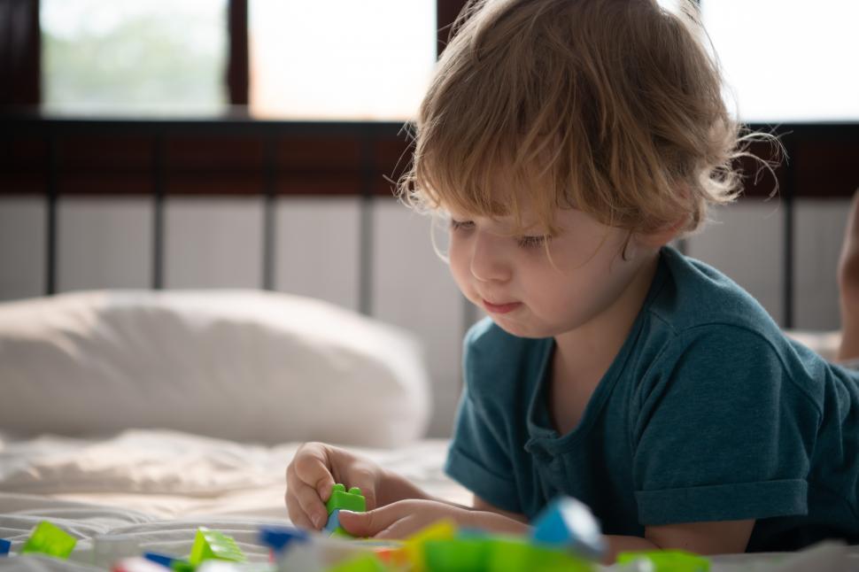 Free Image of Little boy in his bedroom with a new toy purchased by his parents 