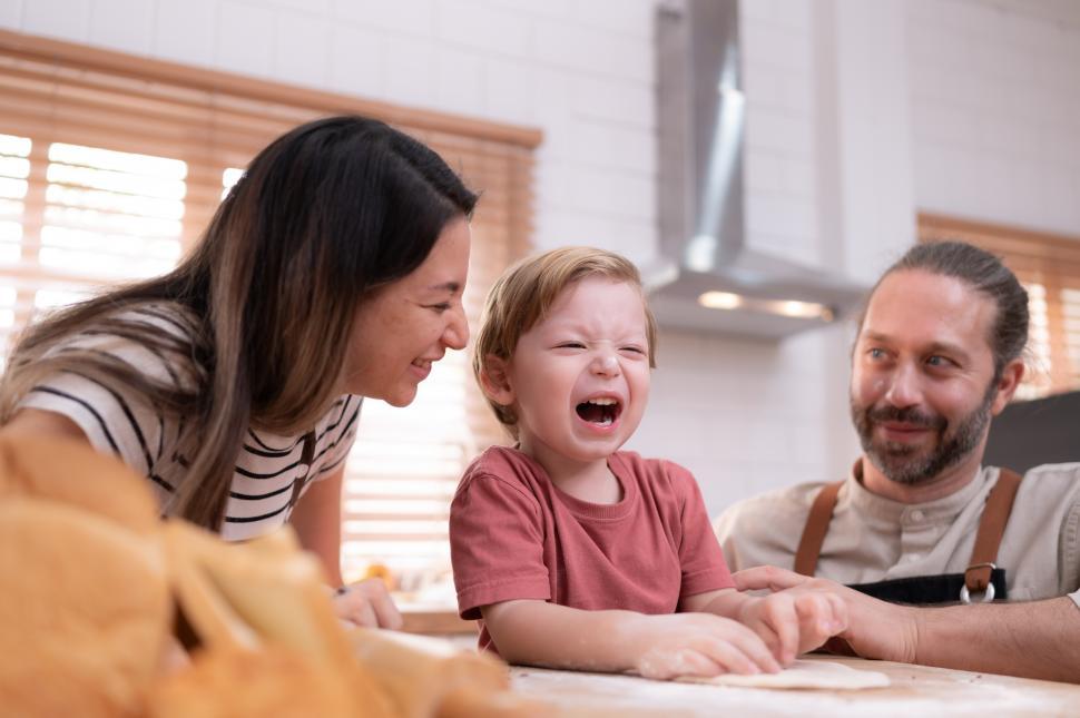 Free Image of Mom and dad in the kitchen of the house with their small children 