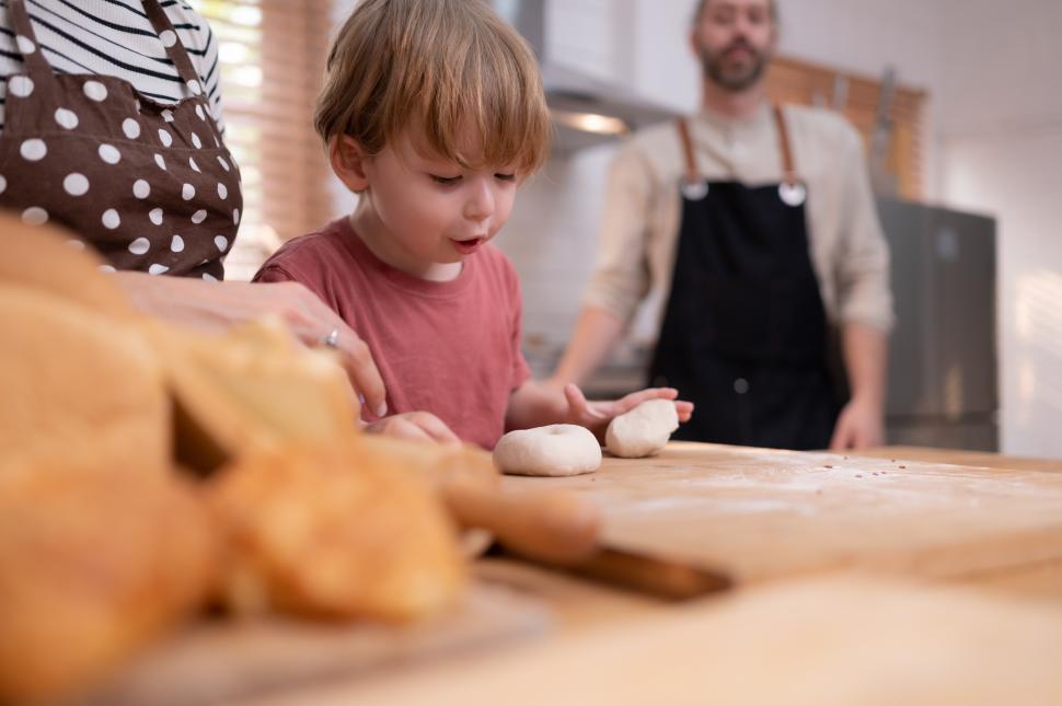 Free Image of Little kid in the kitchen fascinated by fresh dough 