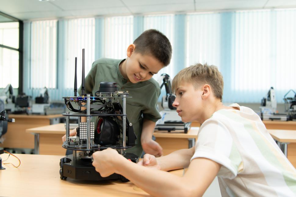 Free Image of Students learning in a robotics lab, working in groups to build a machine 