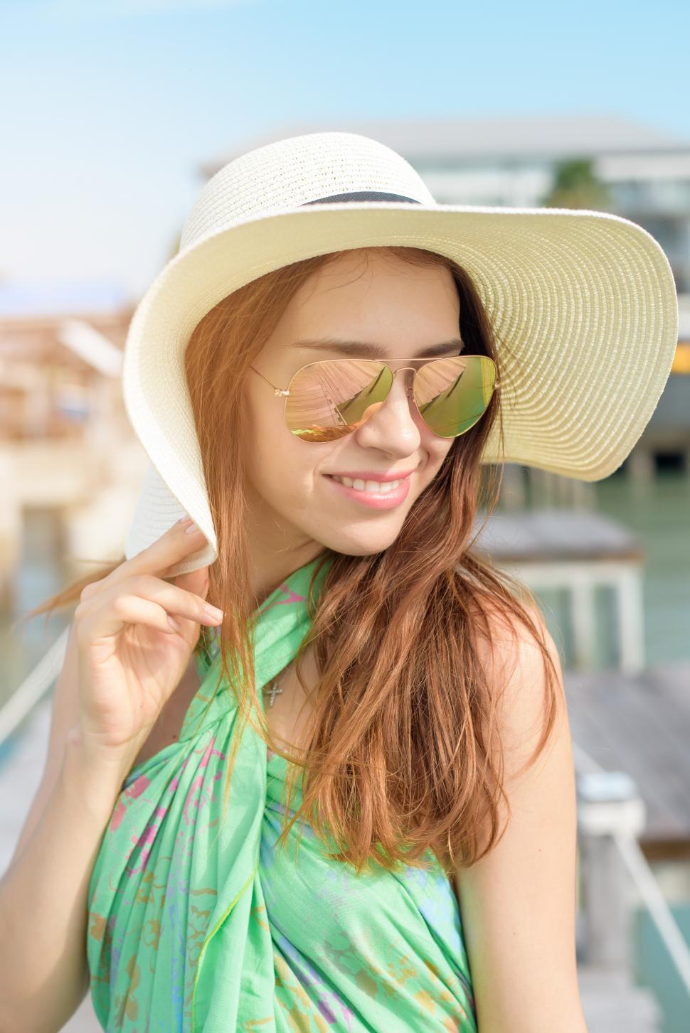 Free Image of Portrait of beautiful woman relaxing on the beach with summer hat and sunglasses 