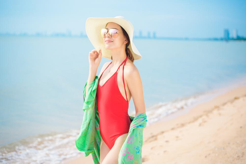 Free Image of Woman in red swimsuit walking on the beach during summer vacation 