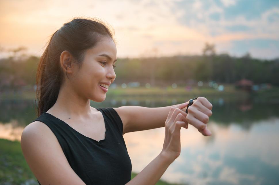 Free Image of A young woman is using smartwatch while exercising outdoors 