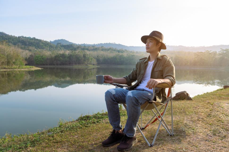 Free Image of Traveling man is drinking hot coffee over mountain and river view 