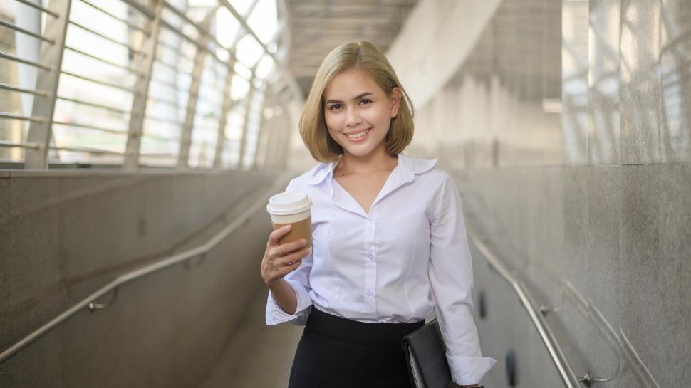 Free Image of Professional woman with coffee standing in a walkway 