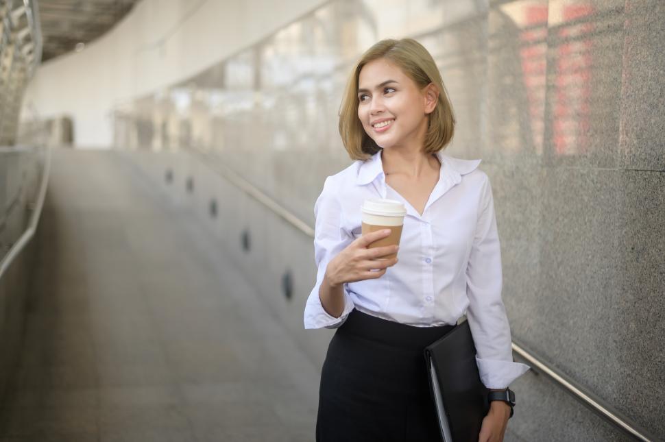 Free Image of Portrait of young Caucasian businesswoman walking with disposable coffee cup 