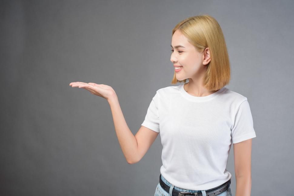 Free Image of Woman holding out her hand to display an item. Fill in your own. 