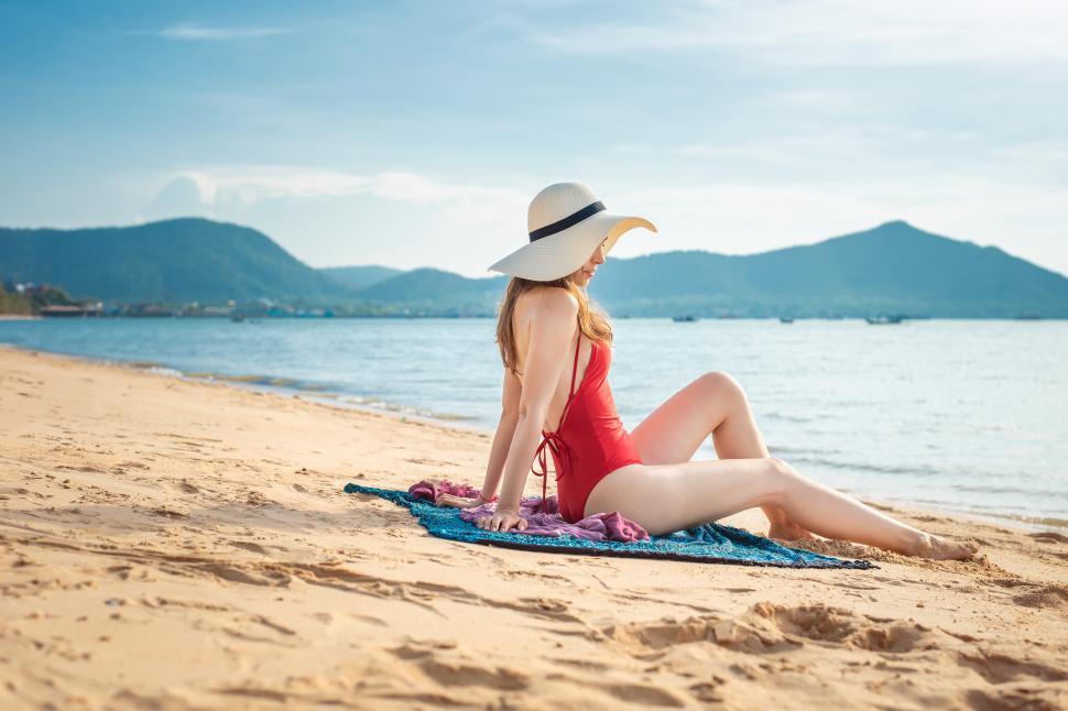 Free Image of Woman in red swimsuit relaxing on a blanket on the summer beach 