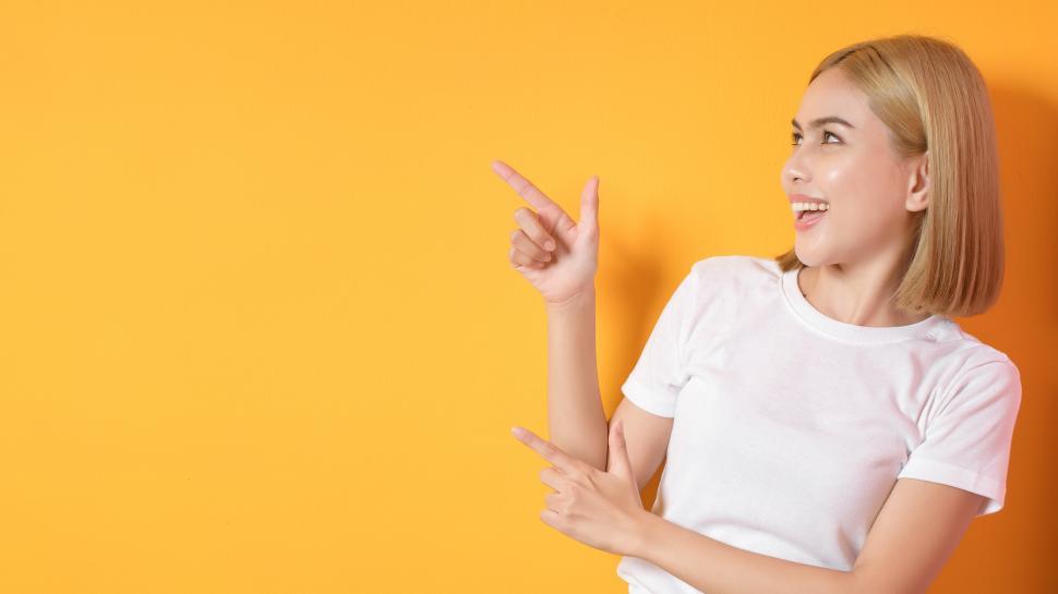 Free Image of Woman on orange background, pointing at blank copyspace. Fill in your own subject. 