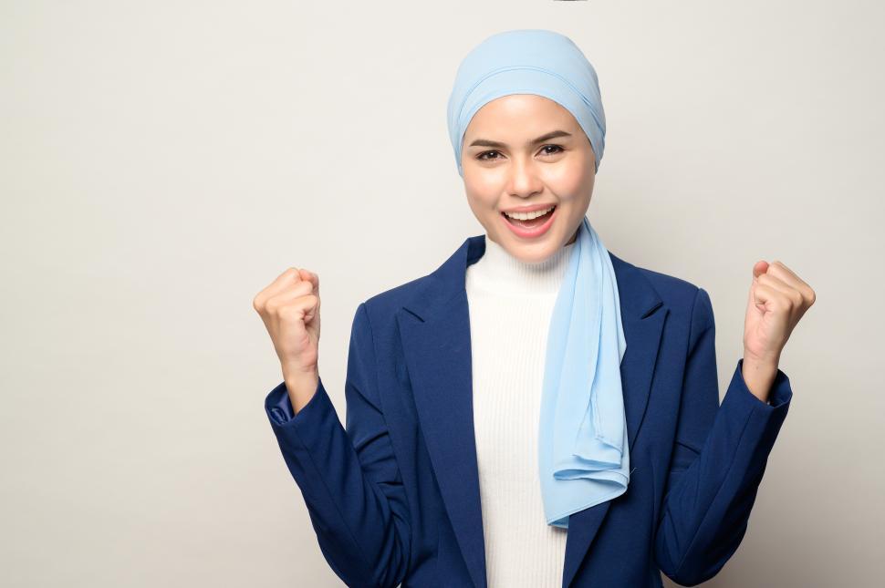 Free Image of young muslim businesswoman with hijab celebrating with clenched hands 