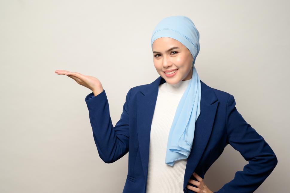 Free Image of Young muslim businesswoman with hijab holding out one hand 