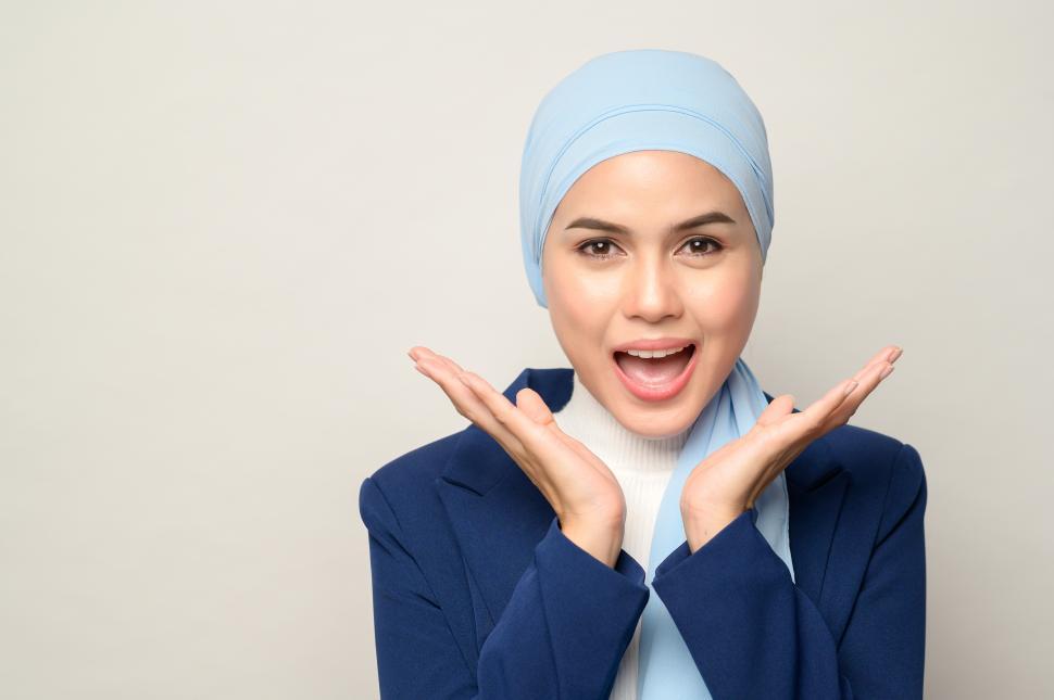 Free Image of Muslim businesswoman with hijab exclaims with open hands 