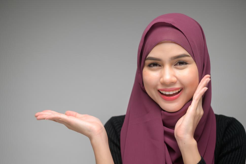 Free Image of Muslim woman over white background studio, holding hand out into copyspace 