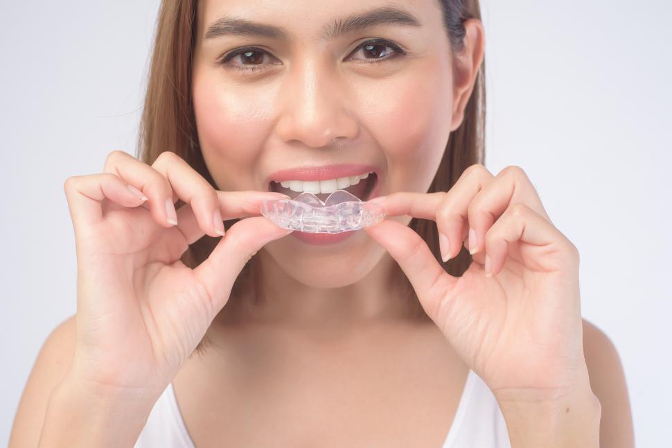 Free Image of Young woman inserting invisible braces to straighten her teeth 