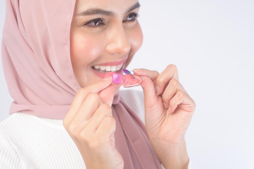 Free Image of Young muslim woman holding colorful retainer for teeth 