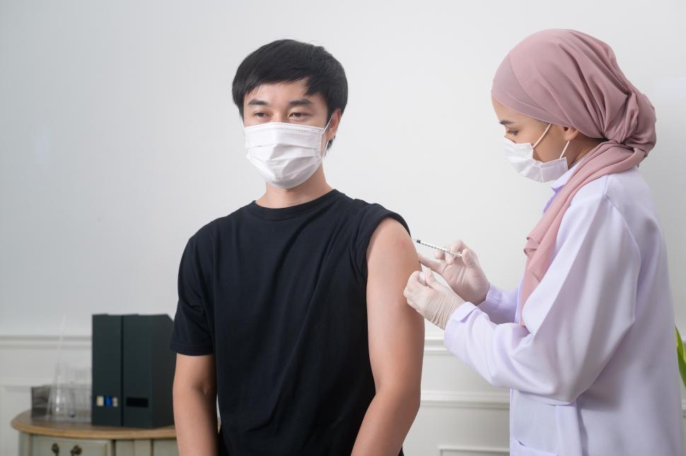Free Image of Female muslim doctor injecting covid-19 vaccine to patient arm, 