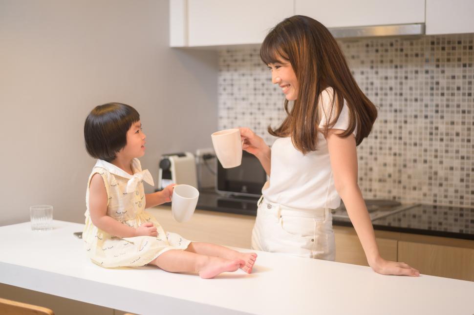 Free Image of Portrait of happy mom and daughter sharing a beverage in kitchen at home 