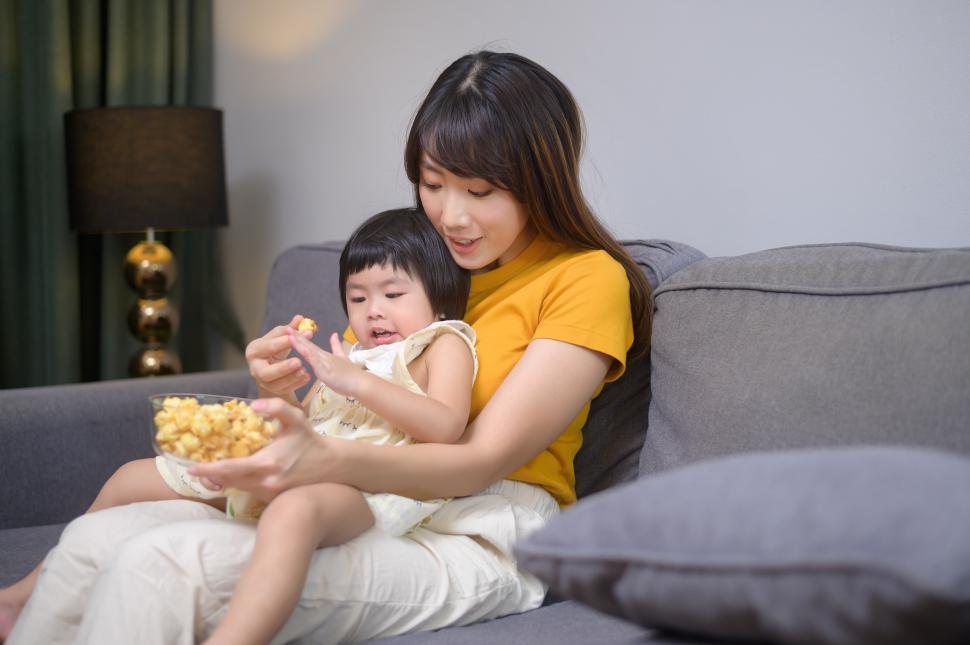 Free Image of Happy mom and daughter watching movie and eating popcorn 