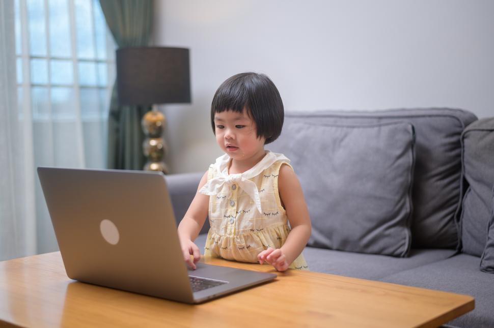 Free Image of Happy very young girl watching something on a laptop computer 