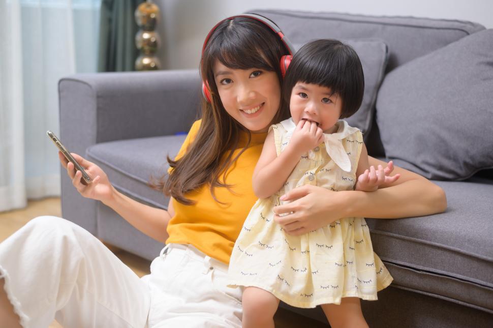 Free Image of Happy mom and daughter listening to music by the living room couch 