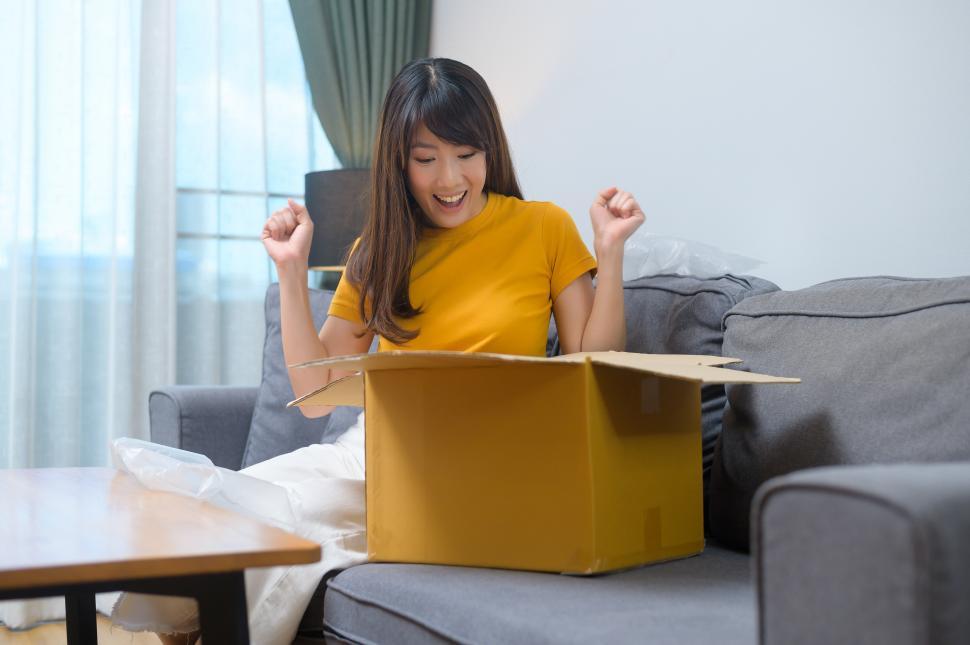 Free Image of Young smiling woman opening cardboard box in living room at home 