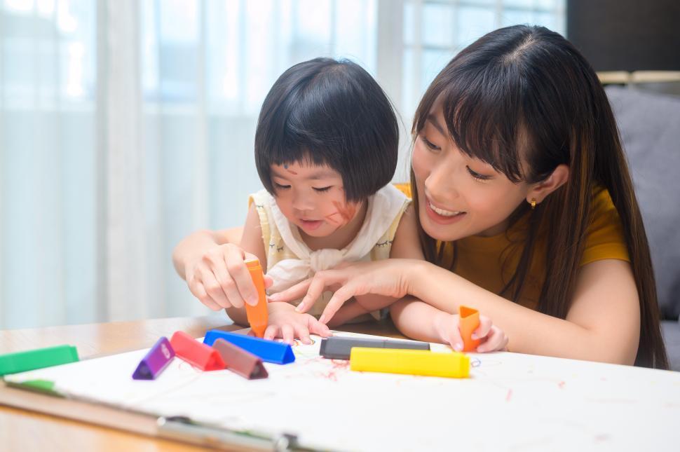 Free Image of Young mom helping daughter drawing with colored markers 