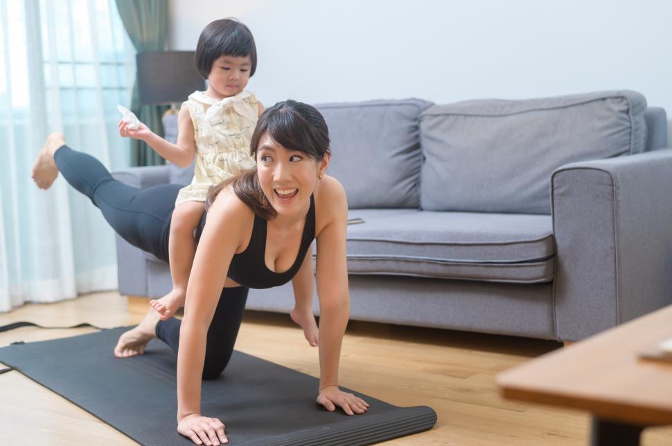 Free Image of Happy young woman is exercising in her young child at home 