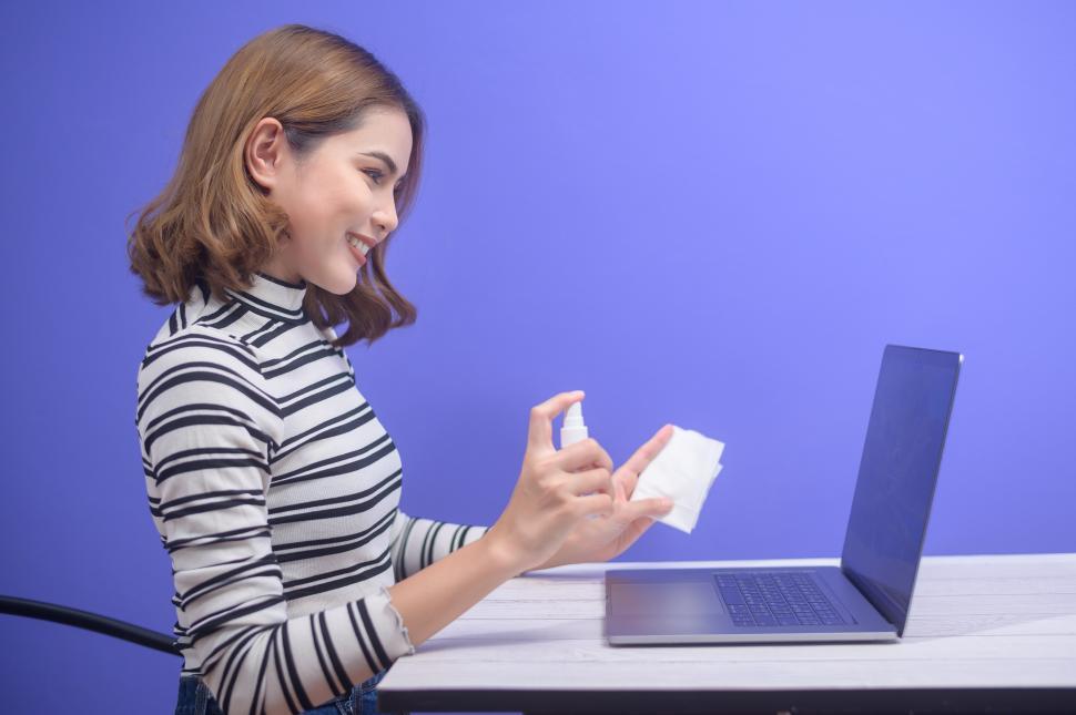 Free Image of Young woman sanitizing computer with alcohol spray - antibacterial, antiviral 