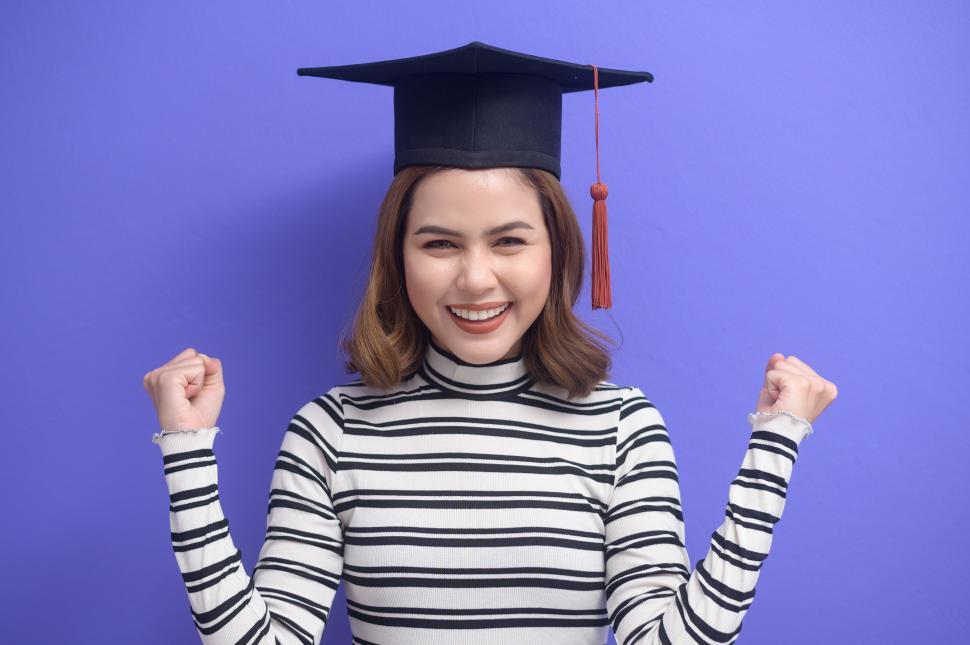 Free Image of Portrait of young woman celebrating graduation over purple background 