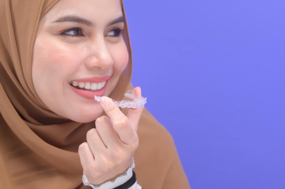 Free Image of Young muslim woman inserting plastic braces tray in studio, dental healthcare 