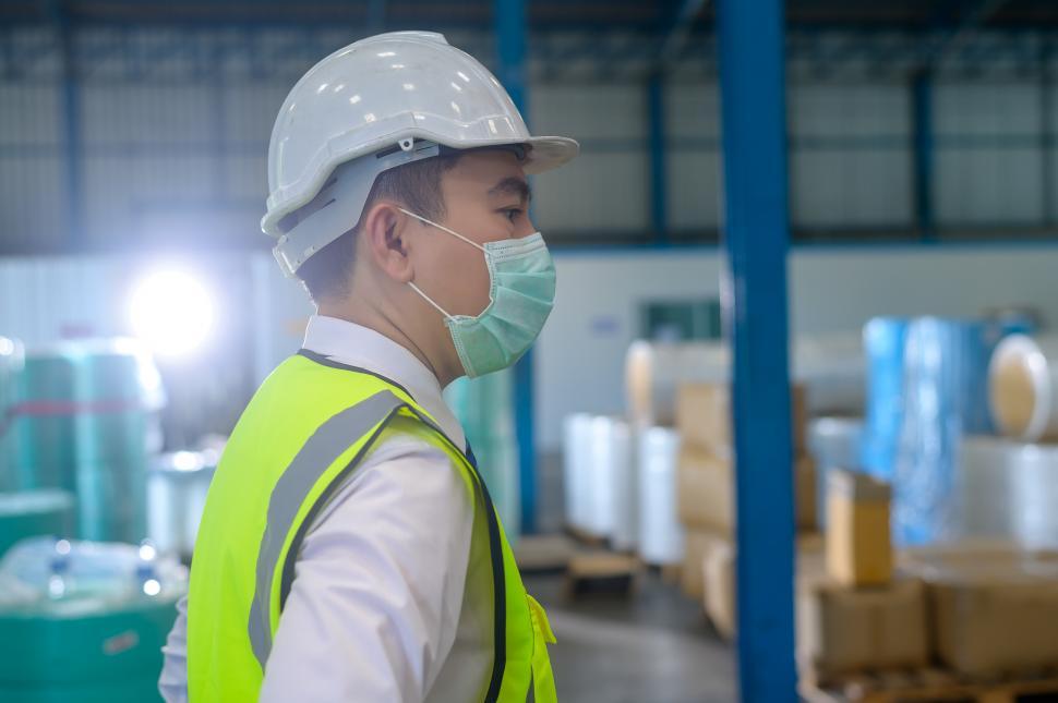Free Image of An engineering wearing medical mask and protective hardhat in factory 