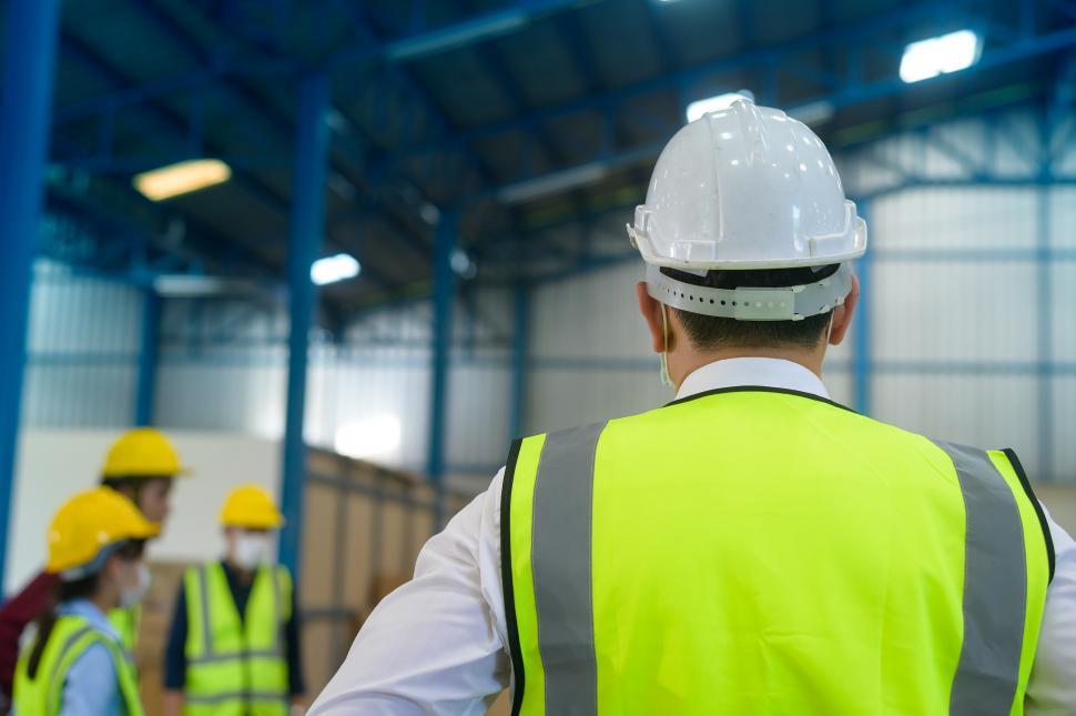 Free Image of Engineer wearing visibility safety vest and hardhat in warehouse floor 