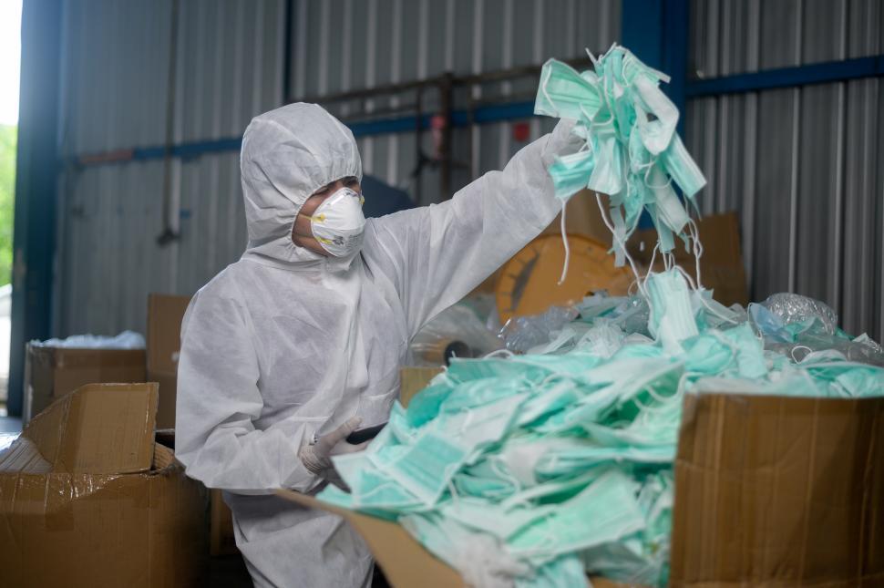 Free Image of Worker with piles of used medical mask in waste recycling facility  