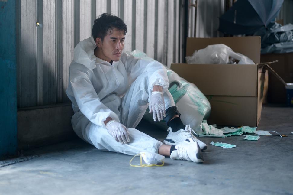 Free Image of Worker in PPE exhausted and after shift in waste recycling facility 